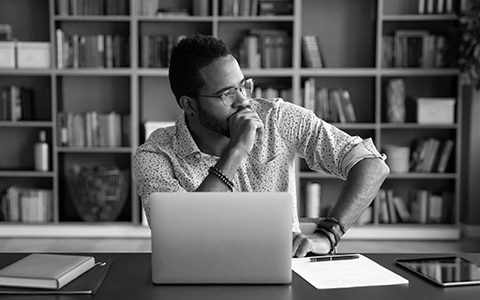 man sitting at a desk in front of laptop searching for home insurance