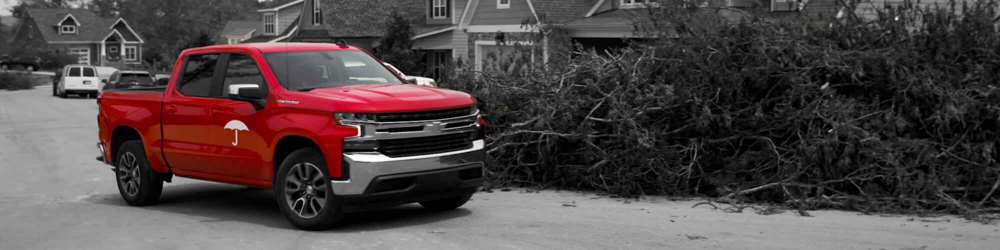 red truck outside of a home with downed trees and damage from severe storm