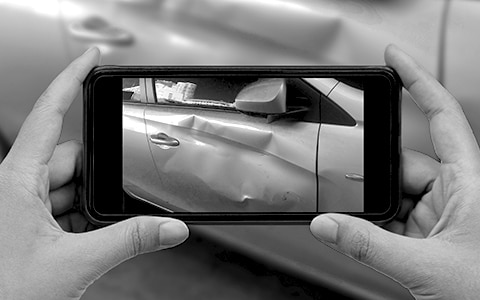 Person holding a smartphone to take photo of car after an accident