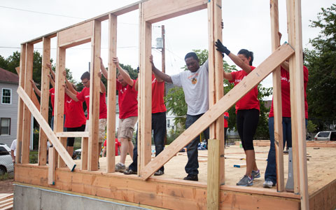a diverse group of people helping build houses in their community