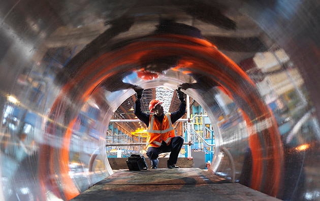 looking through a metal pipe towards a worker