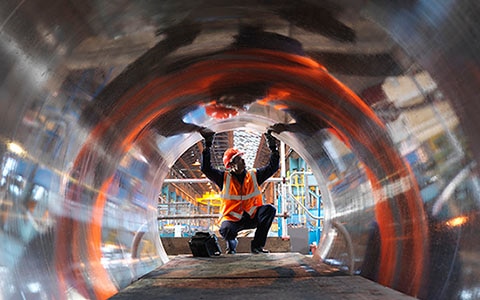 looking down metal pipe with worker at the end