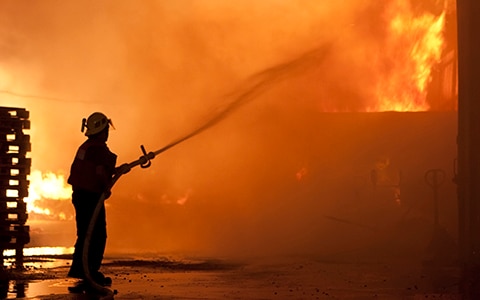 Firefighter fighting wood-framed fire