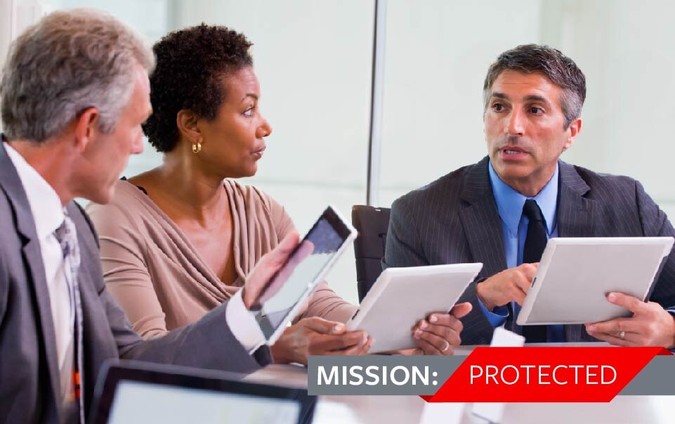Three professionals meeting at a table looking at tablets