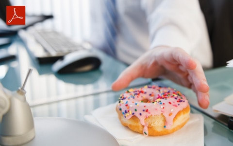 person at desk in the office reaching for a donut