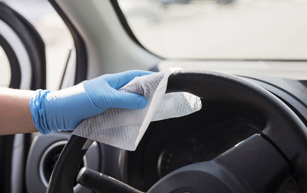 gloved hand wiping steering wheel of car