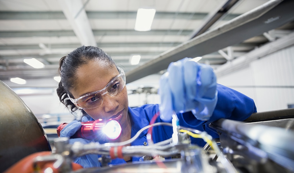 woman working on machine wearing safety goggles