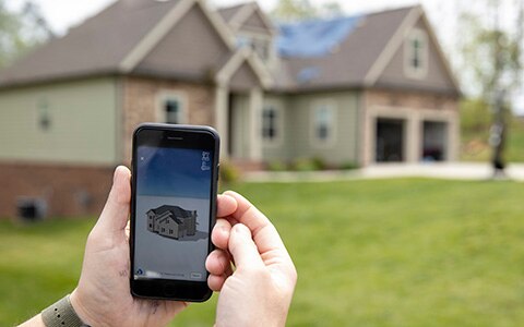 Property inspector measuring a house with virtual measurement phone app
