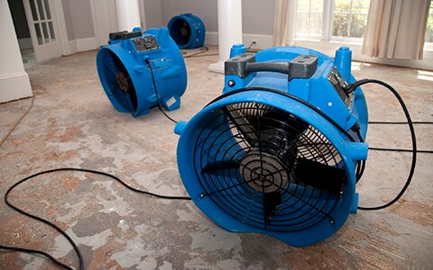 Large fans drying a room with water damage