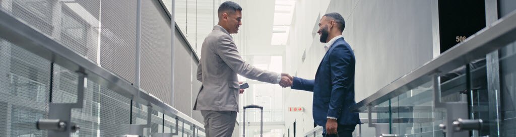 Two men shaking hands at the airport.