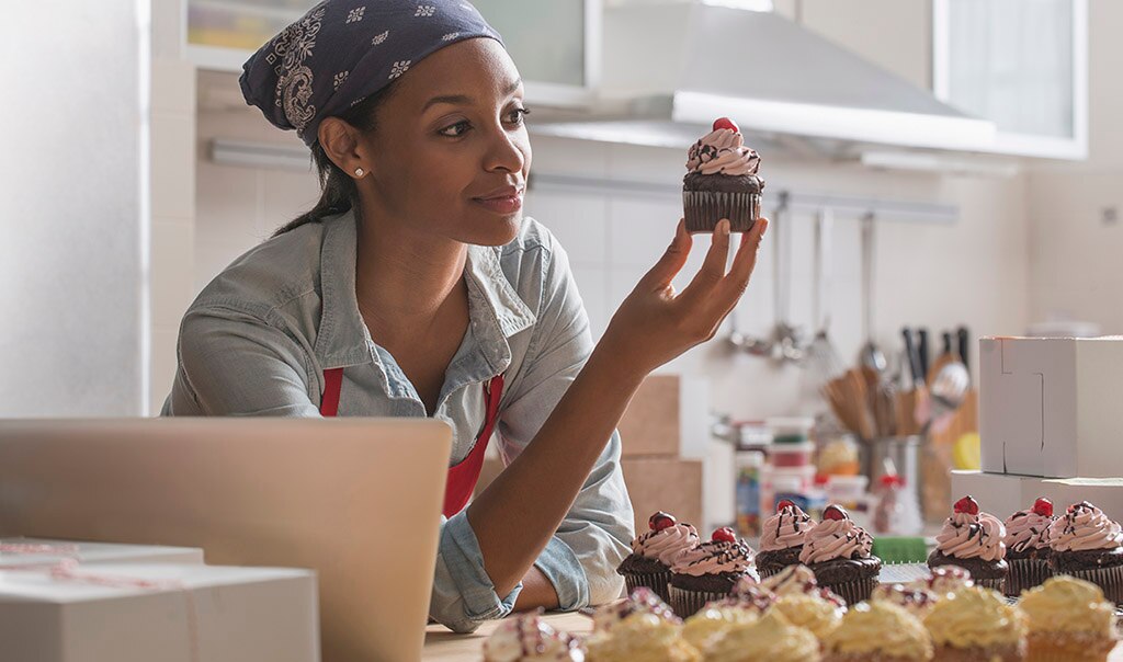small business owner in her bakery looking at a cupcake, Benefits of Insurance Bundling for Small Business Customers