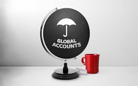 A black globe with a white umbrella logo and the words, Global Accounts, sitting on a tabletop next to a red coffee cup.