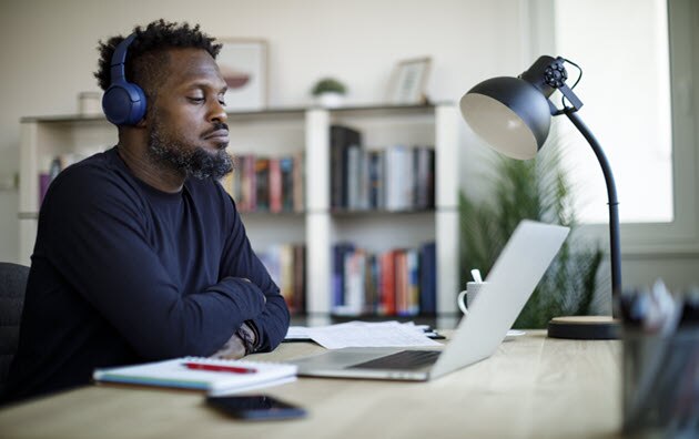 Man with headphones on sitting at desk with laptop