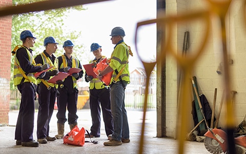 Construction Risk Management - construction workers standing in a circle in a warehouse of tools