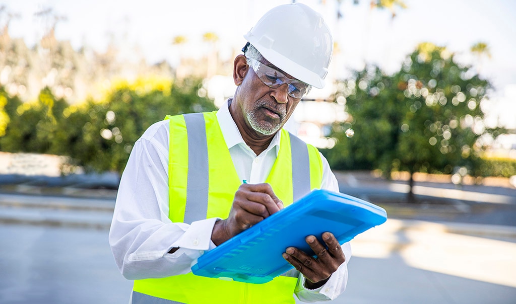 Construction worker looking over paperwork on a clipboard