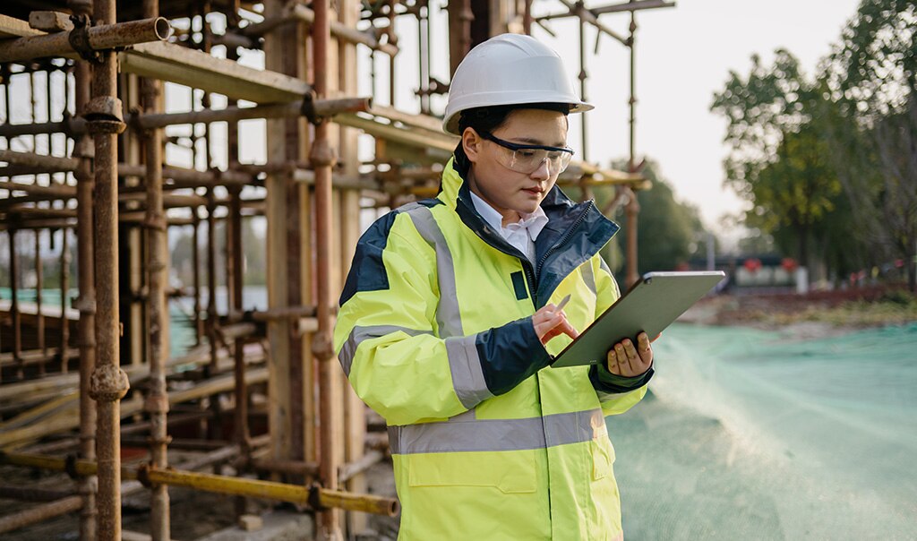 Female construction worker at job site looking at tablet