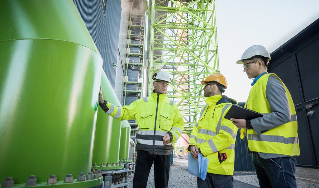 Three men talking at a power plant.