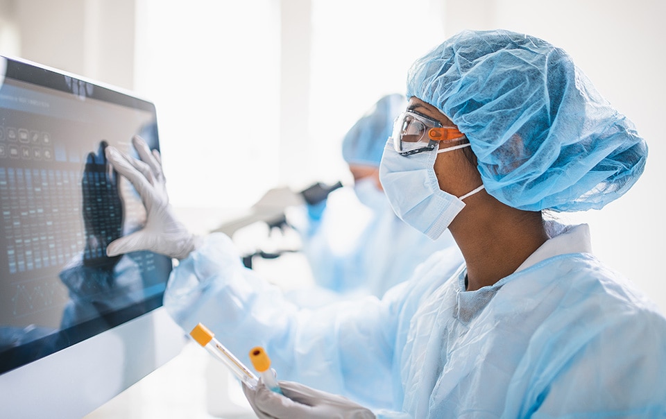 scientist in scrubs tending to a screen