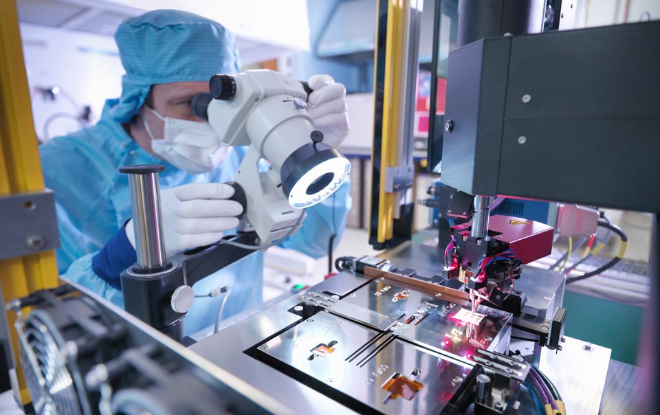 High-tech manufacturer looking through microscope