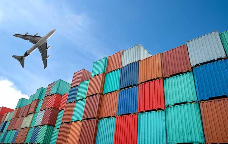 plane flying over shipping containers