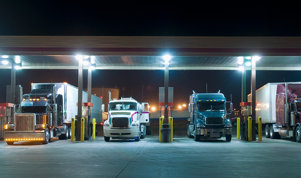Image of trucks at a truck stop lined up at a gas station. Cargo Pilferage and Broken Seal Events Can Be Costly [Infographic].