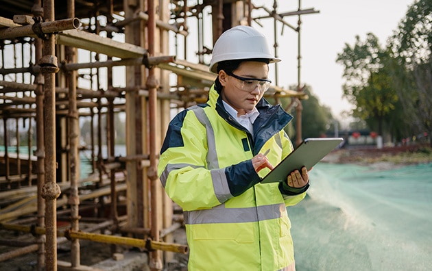 Female construction worker at job site looking at tablet