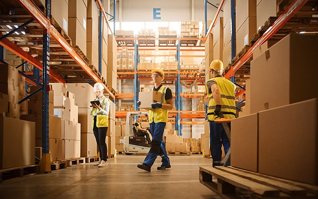 Warehouse workers moving boxes and inventory inside a warehouse.