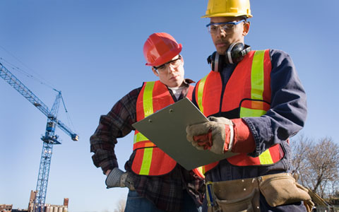 Construction workers on crane site reviewing OSHA standards