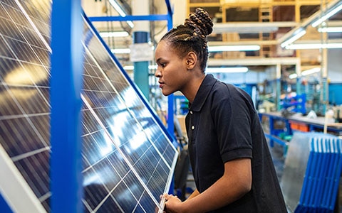 woman looking at solar panels in a factory