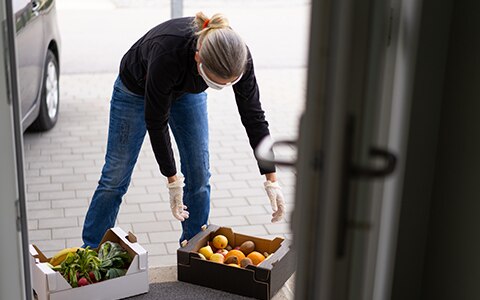 A woman carrying baskets of food into a doorway