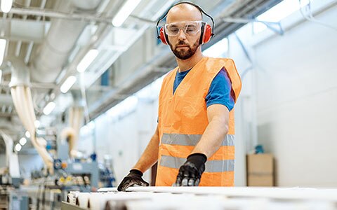 A man working in a factory, wearing safety gear, Resuming Building Operations After a Shutdown