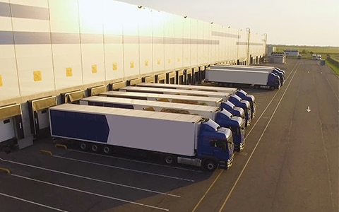 freight trucks lined up against a building for loading/unloading, The Evolution of the Freight Broker Model Brings New Risks