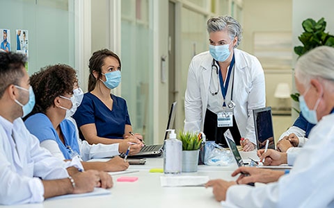 Healthcare professionals wearing masks seated around a conference table