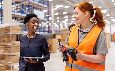 two warehouse employees, holding clipboard and digital tablet