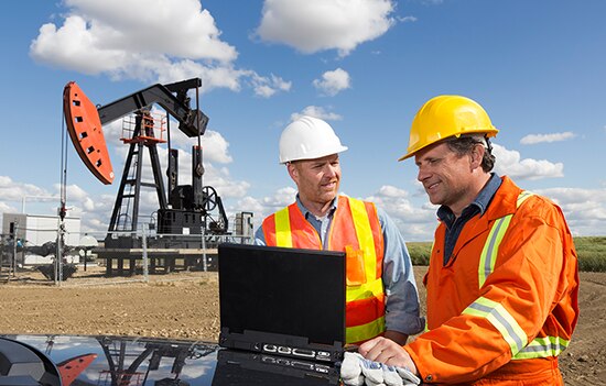 Two guys looking at laptop at oil dump