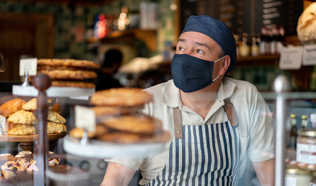 man behind a bakery counter wearing a face mask. How to Scale Products and Services To Increase Profitability