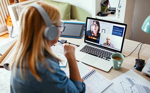 An employee meeting with coworkers virtually through a laptop.