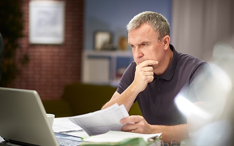 man sits at desk at home concentrating on his computer, How to Streamline Operational Processes and Procedures