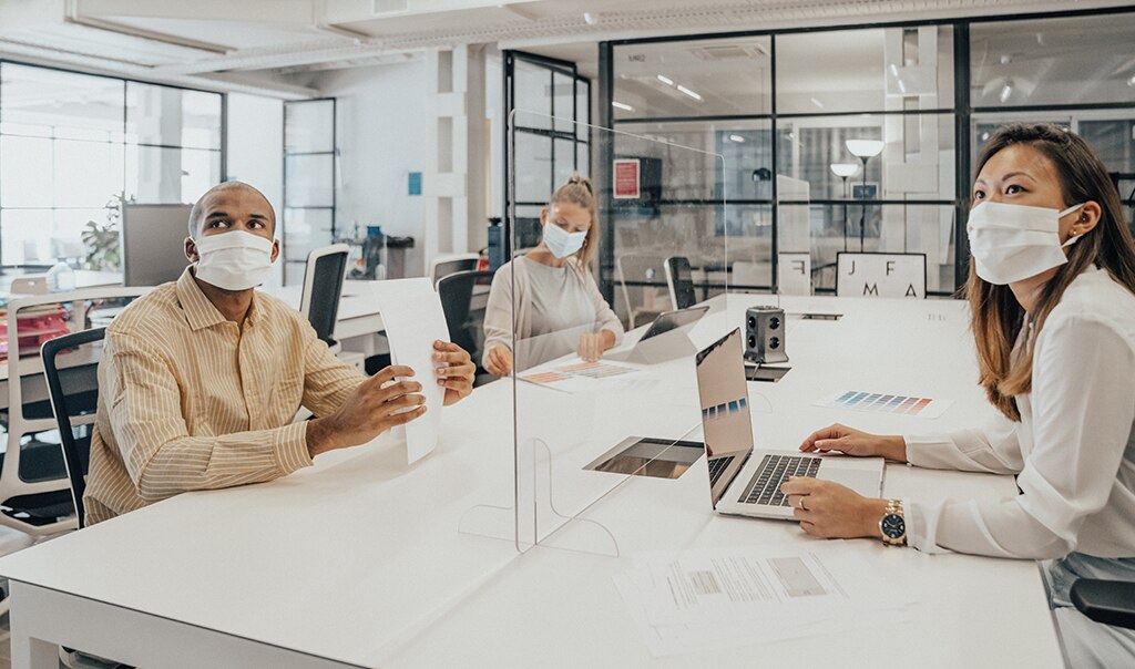 Woman with mask on wiping down desk