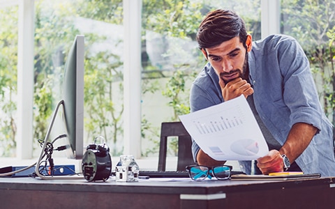 man at desk looking at printed financial statement, Should You Pivot Your Business Model
