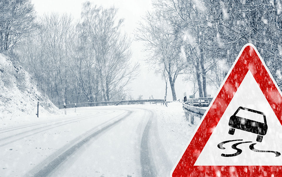 Empty snowy road with a slippery road sign