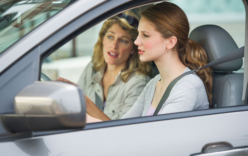 Parent teaching teen daughter how to drive