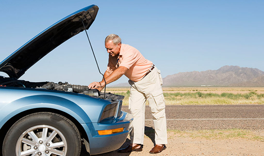 Man looking under hood of car after car breakdown