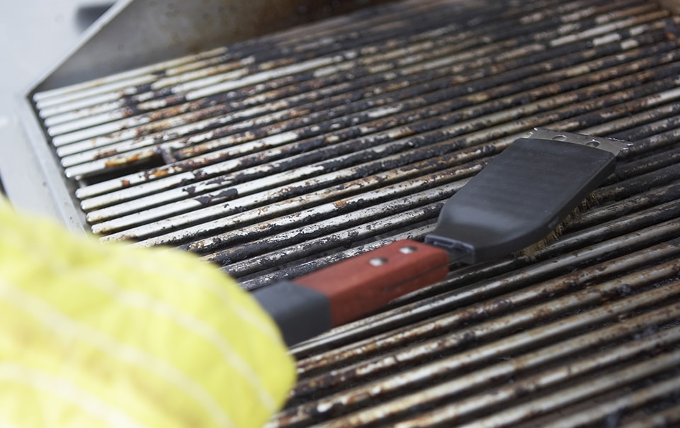 Person cleaning a gas grill