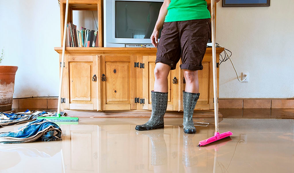 person with rain boots on cleaning up water 