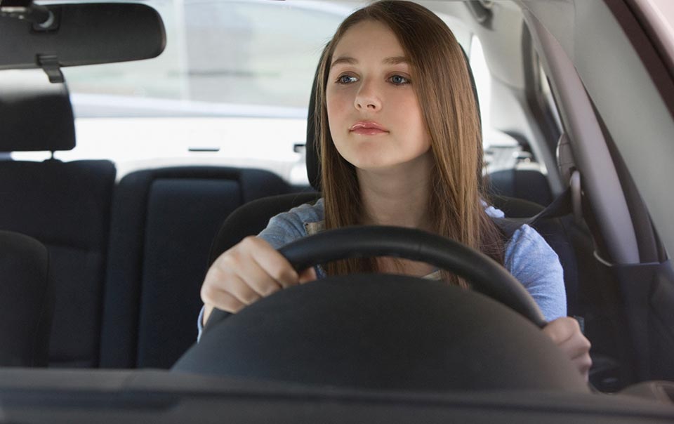 Teenage carefully driving behind the wheel of a car