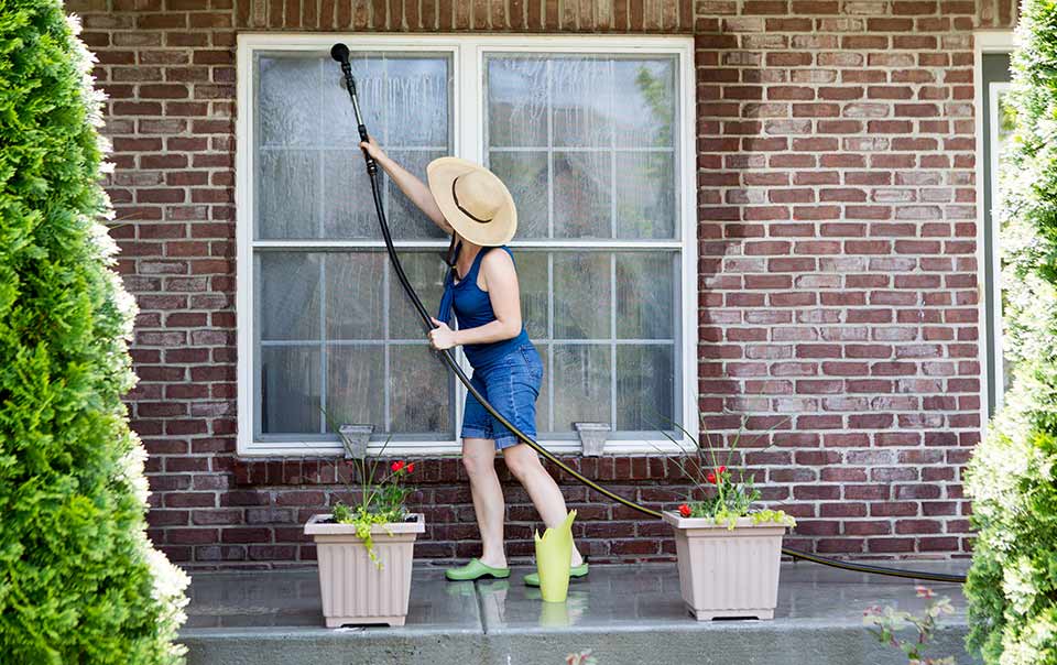 Woman cleaning windows as part of summer maintenance