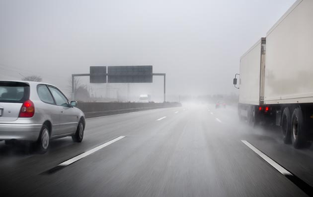 Cars and trucks driving safely on the highway in strong wind and rain