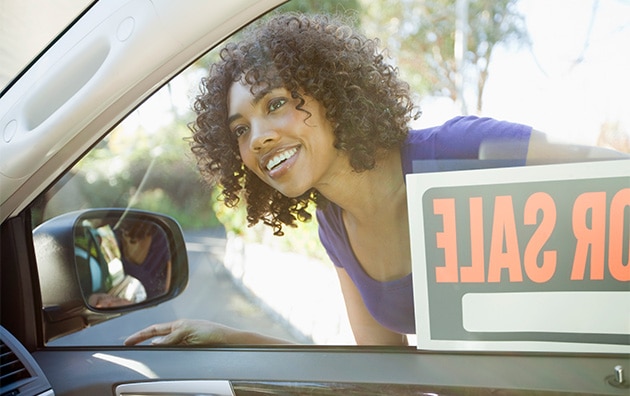 woman looking through car window with for sale sign on it