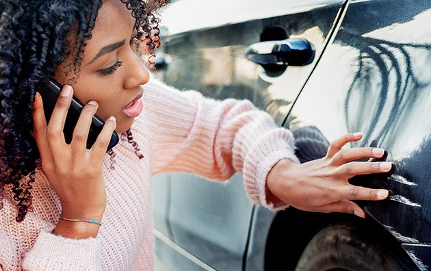 a young woman is examining scratches and dents along the side of her car